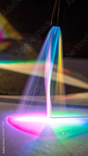 Vibrant light projection featuring a prismatic spectrum of colorful beams emerging from a concentrated focal point on a dark background