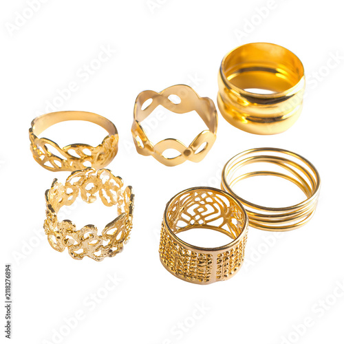 Six gold rings with varied textures and designs, displayed against a stark black background for emphasis