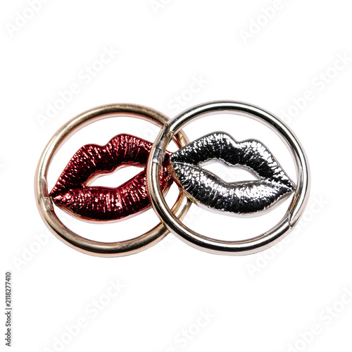 Two metallic lip-shaped objects with texture and glitter, within golden and silver rings, intertwined on a black background
