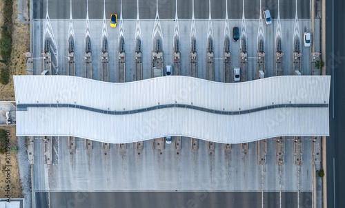 Baillargues, France - 18 July 2026: Aerial view of a modern highway toll plaza with a wave-shaped roof, lane markings, and scattered vehicles creating a geometric composition.
