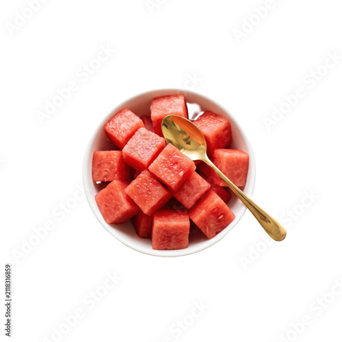 Fresh diced watermelon cubes in a bowl with a gold spoon isolated on white.