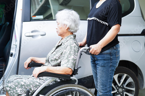 Caregiver help Asian elderly woman disability patient get in her car.