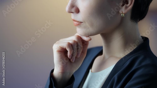 A middle-aged woman thinking in a dimly lit room. Serious, questioning, business owner, manager, decision-making, choices, worries, anxiety, concern, changing jobs, dissatisfaction.