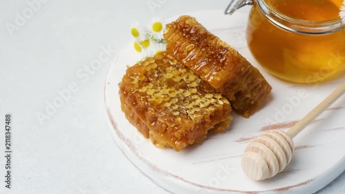Honeycomb pieces and jar of honey with flowers on a white background
