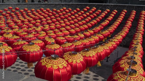 Rows of vibrant red Chinese lanterns hanging against an ancient brick wall background.