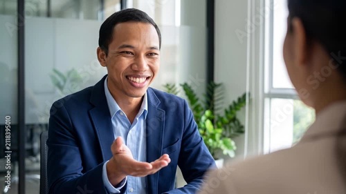 Happy Indonesian professional business man executive hr or bank manager, lawyer or financial advisor having job interview or business conversation consulting client at corporate office meeting.