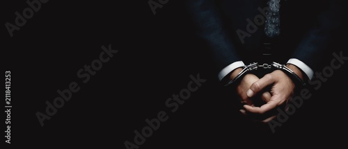 Man in handcuffs against a dark background.