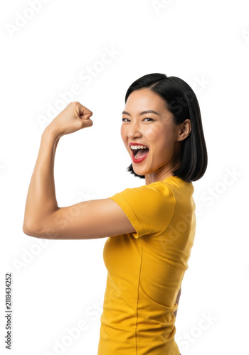 young athletic east asian woman in a vibrant yellow t-shirt intensely flexing bicep, yelling triumphantly on shadowless white studio backdrop. commercial female empowerment concept