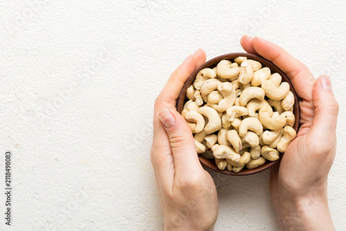 Woman hands holding a wooden bowl with cashew nuts. Healthy food and snack. Vegetarian snacks of different nuts