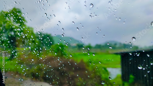 rain drops on a glass of the window of the car in the rainy season.