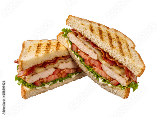 Two halves of a delicious grilled chicken and bacon club sandwich with melted cheese and fresh vegetables.