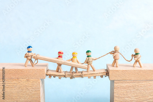 Wooden Figures Building a Bridge Together