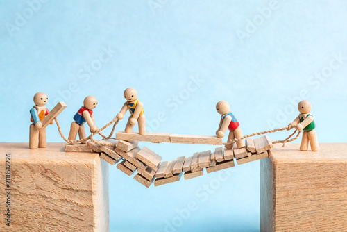 Wooden Figures Building a Bridge Together