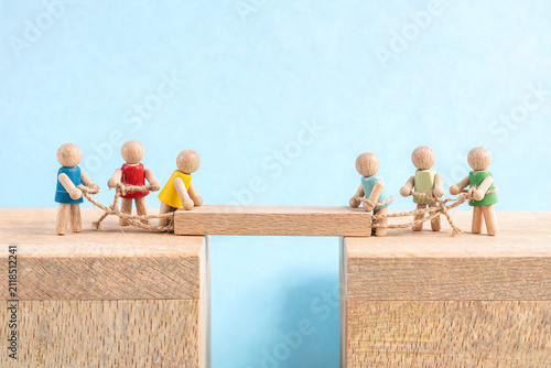 Wooden Figures Building a Bridge Together