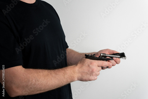 Foto Cropped view of man in black t shirt separating slide mechanism from handgun frame with recoil spring visible on white background
