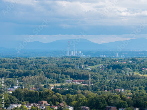 Fotografía Industrial power plant contrasting natural landscape with forest, mountains, and