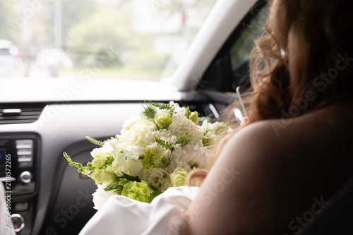 Картината върху платно A bride with a bouquet of flowers sitting in a car.