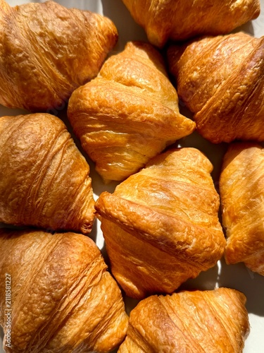 фотографія Freshly baked French croissants under warm direct sunlight, close up texture bac
