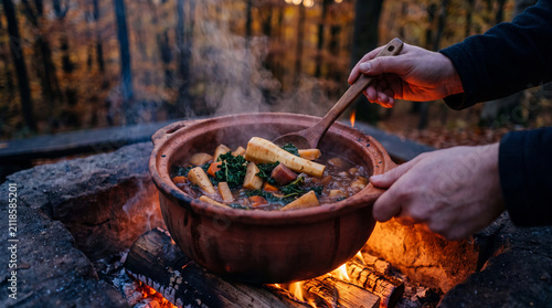 Cooking a stew in a clay pot over a campfire in an autumn forest