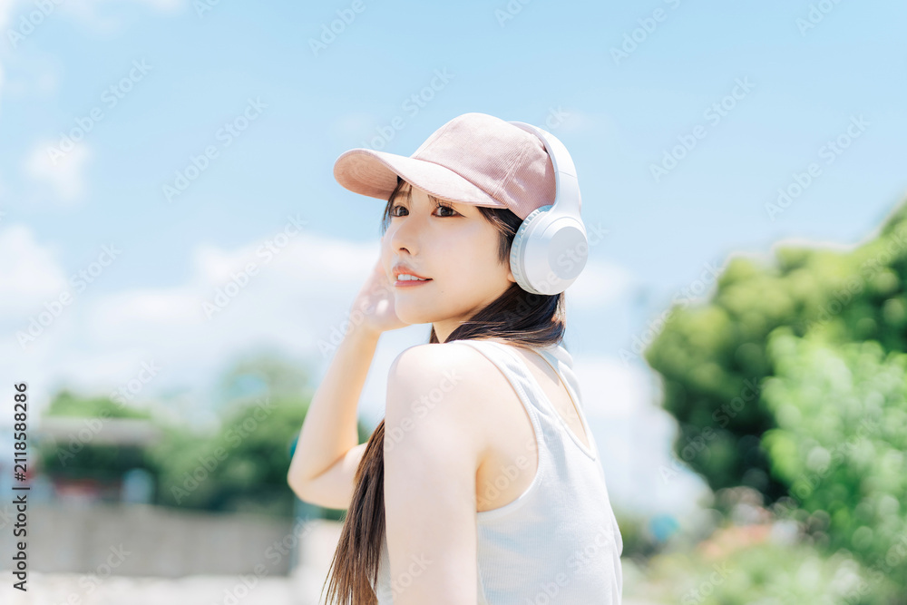 Fototapeta premium 屋外で音楽を聴く若い女性