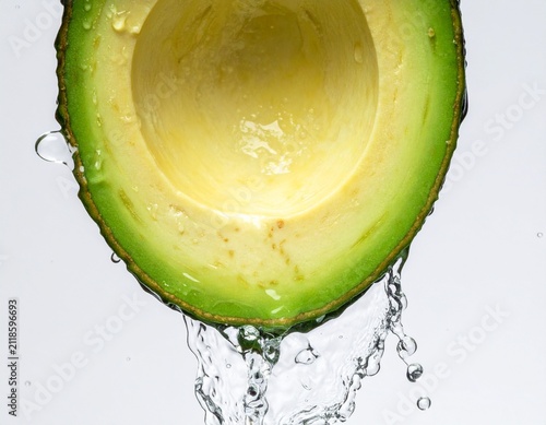 Fresh Half Avocado Being Washed with Pure Splashing Water Isolated on a Clean White Background for Healthy Diet and Nutrition Concept