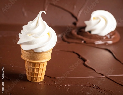 Delicious soft serve vanilla ice cream cone resting on a melted dark chocolate background