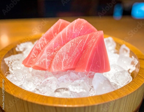 Fresh raw tuna sashimi slices served on crushed ice in a wooden bowl at a Japanese restaurant