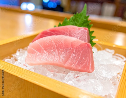 Exquisite fresh raw tuna sashimi glistening on a bed of crushed ice, meticulously presented in a traditional wooden box at a high-end Japanese culinary establishment