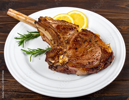 Grilled Lamb Chop Seasoned with Fresh Rosemary and Citrus Slices on a White Plate