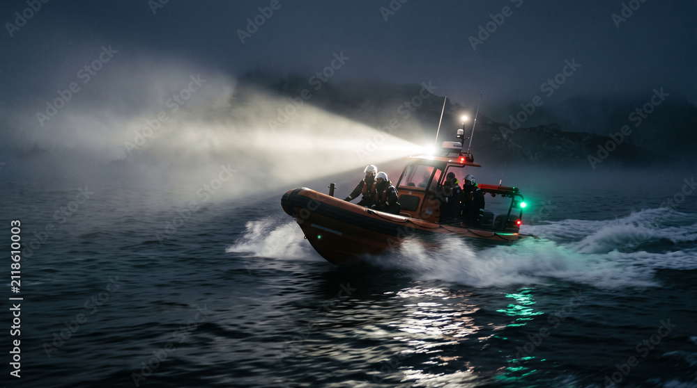 Fototapeta premium Rescue boat with searchlights operating at night in misty ocean