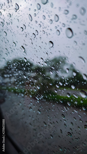 rain drops on a glass of the window of the car with a road in the background.