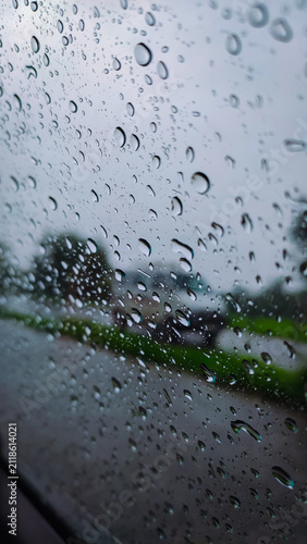 rain drops on a glass of the window of the car with a road in the background.
