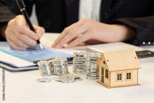 Quadro su tela Signing mortgage documents with house model and stacked coins