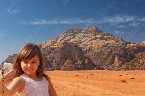 Little tanned girl is taking a selfie in Wadi Rum desert.  Jordan. Horizontally. 
