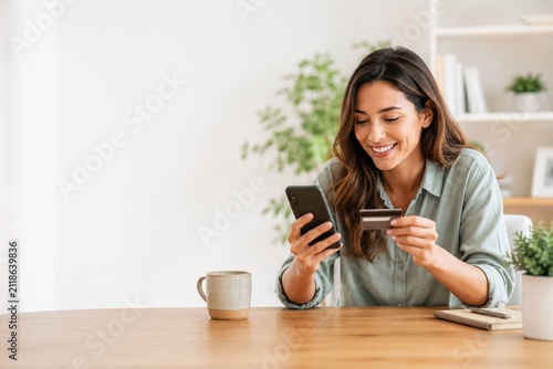 Smiling woman shopping online with smartphone and credit card at home, ecommerce payment and digital banking concept with copy space