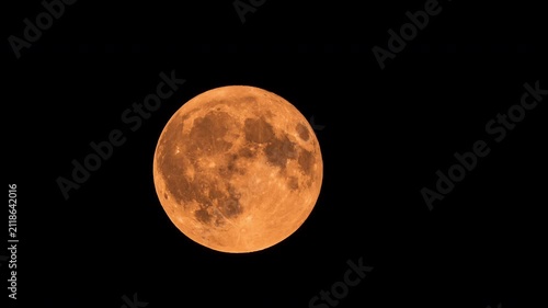 Massive orange full moon rising on black background time lapse