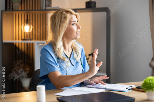 Fotografie Healthcare professional wearing blue scrubs sitting at a clinic desk, making a d