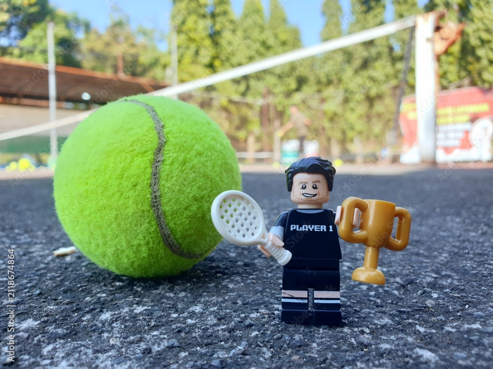 Fototapeta premium Indonesia - August 31, 2024 : Mini toy of acrion figure at tenniscourt with blurred background. Sport photography concept design. Young man athlete at tennis club.