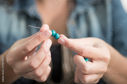 Close-up of woman stringing beads to create a necklace