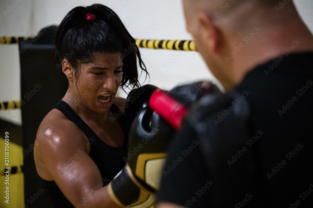 Fototapeta premium Female Boxer Training With Coach Hitting Focus Mitts During Intense Gym Workout
