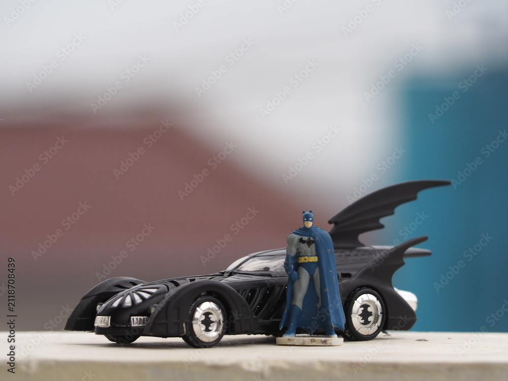 Fototapeta premium Indonesia - December 16, 2018 : Mini toy of action figure at table with blurred background. Macro toy photography concept design. Minifigure of Batman character from DC Comics film with batmobile.