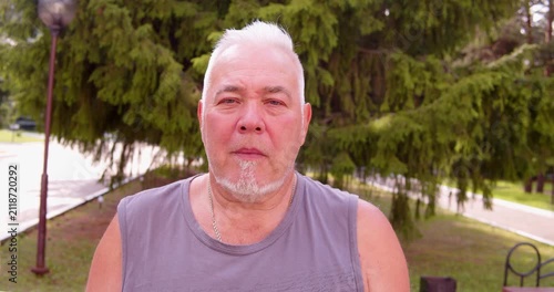 Man with a cheerful expression looks at the camera outdoors.