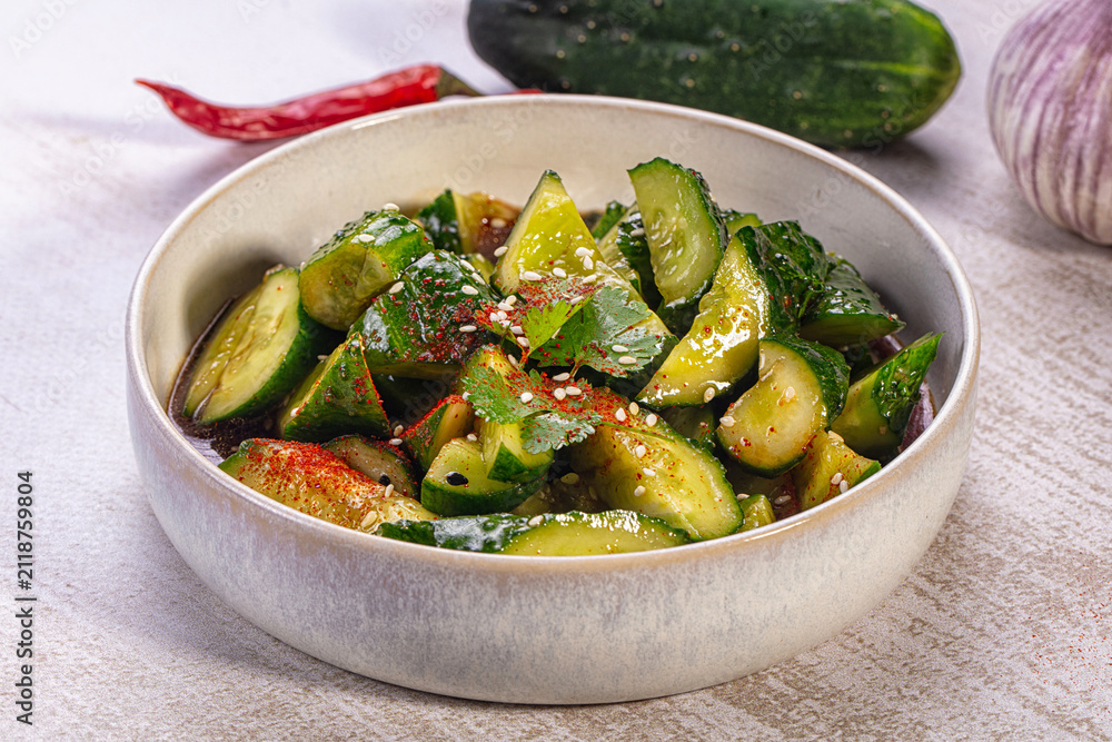 Fototapeta premium Smashed cucumber salad with sesame seeds and chili flakes in ceramic bowl