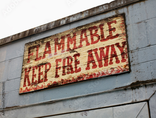 A painted warning sign on the exterior of a building. Flammable, keep fire away.