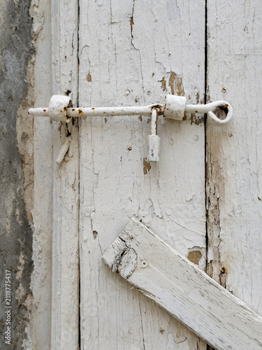 Weathered Door, close up of a wooden door with a metal bolt and padlock, peeling white paint.
