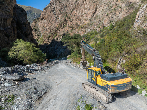 Excavator on unpaved road in mountainous gorge