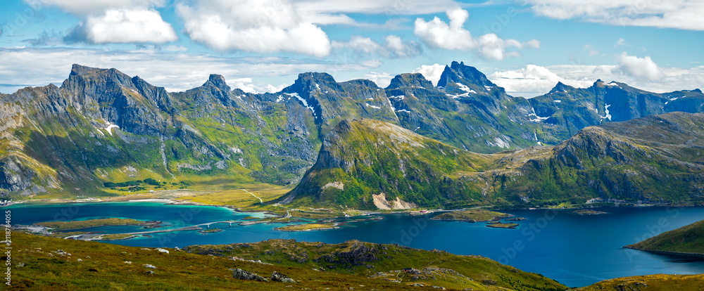 Obraz premium Nordland, Norway - 12.07.2020: Panoramic view of jagged green mountains and turquoise fjords under a bright summer sky