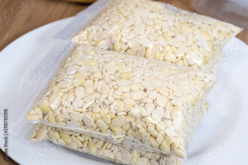 Peeled split soybeans packed tightly in a clear plastic zipper pouch, presented on a plain white surface. Highlighting raw plant based ingredients, prep work