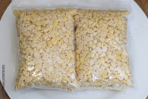 Peeled split soybeans packed tightly in a clear plastic zipper pouch, presented on a plain white surface. Highlighting raw plant based ingredients, prep work