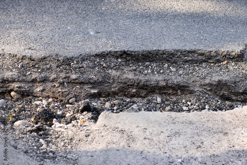 Foto Damaged asphalt road with a deep pothole and broken pavement surface
